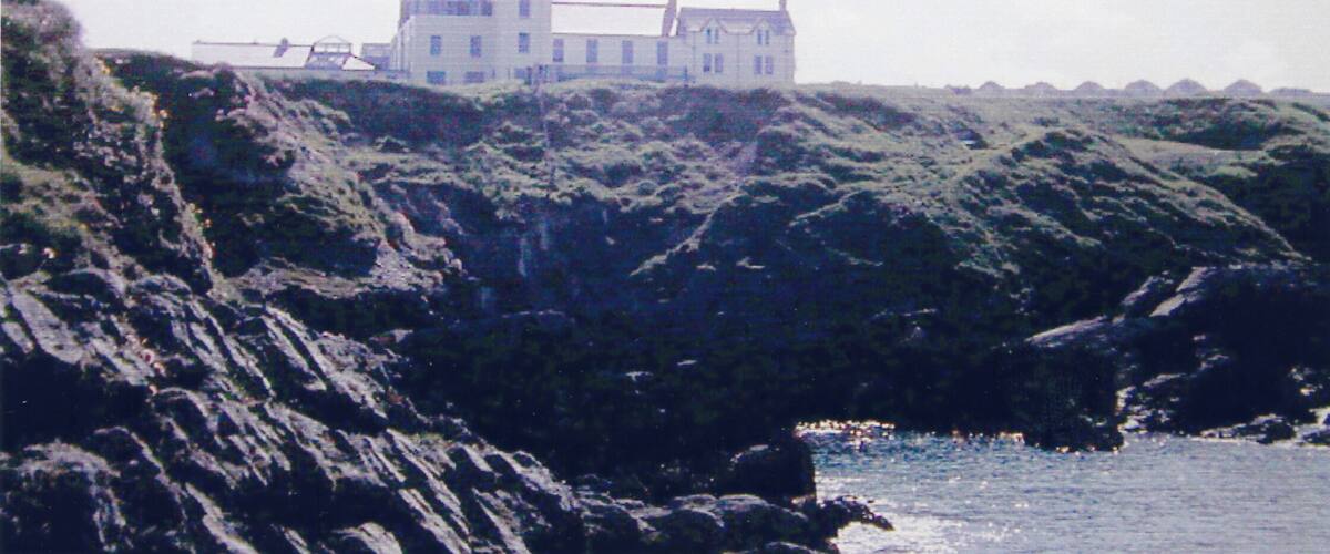 A coastal house on a rocky cliff overlooking the sea.
