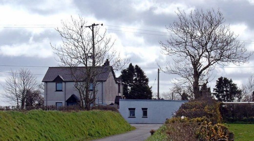 A rural road with a house and a small building on the left.
