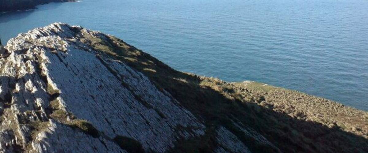 A coastal landscape with rocky cliffs and calm sea.