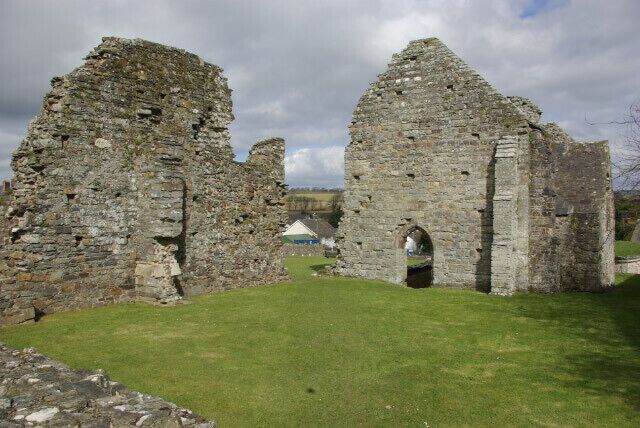 A historical stone structure with ruins and a grassy foreground.