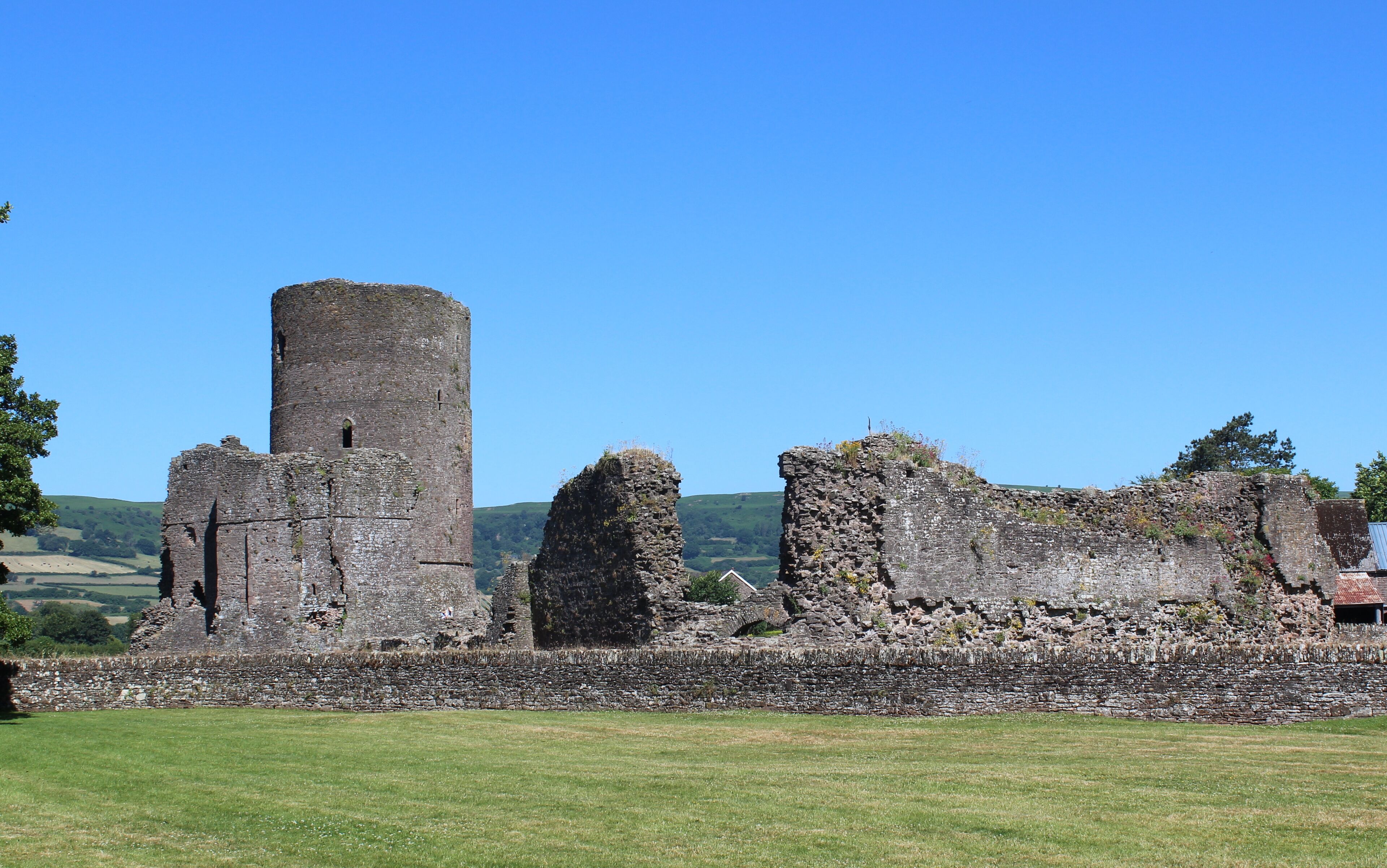 A medieval castle ruin with a tall tower and several other structures.