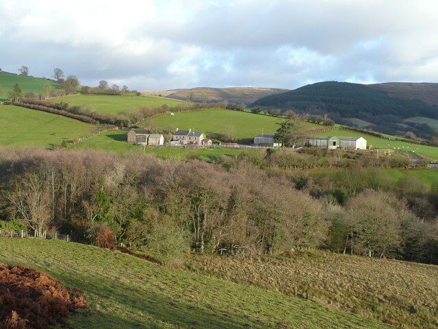 Rolling hills, a farmhouse, and a barn in a rural landscape.