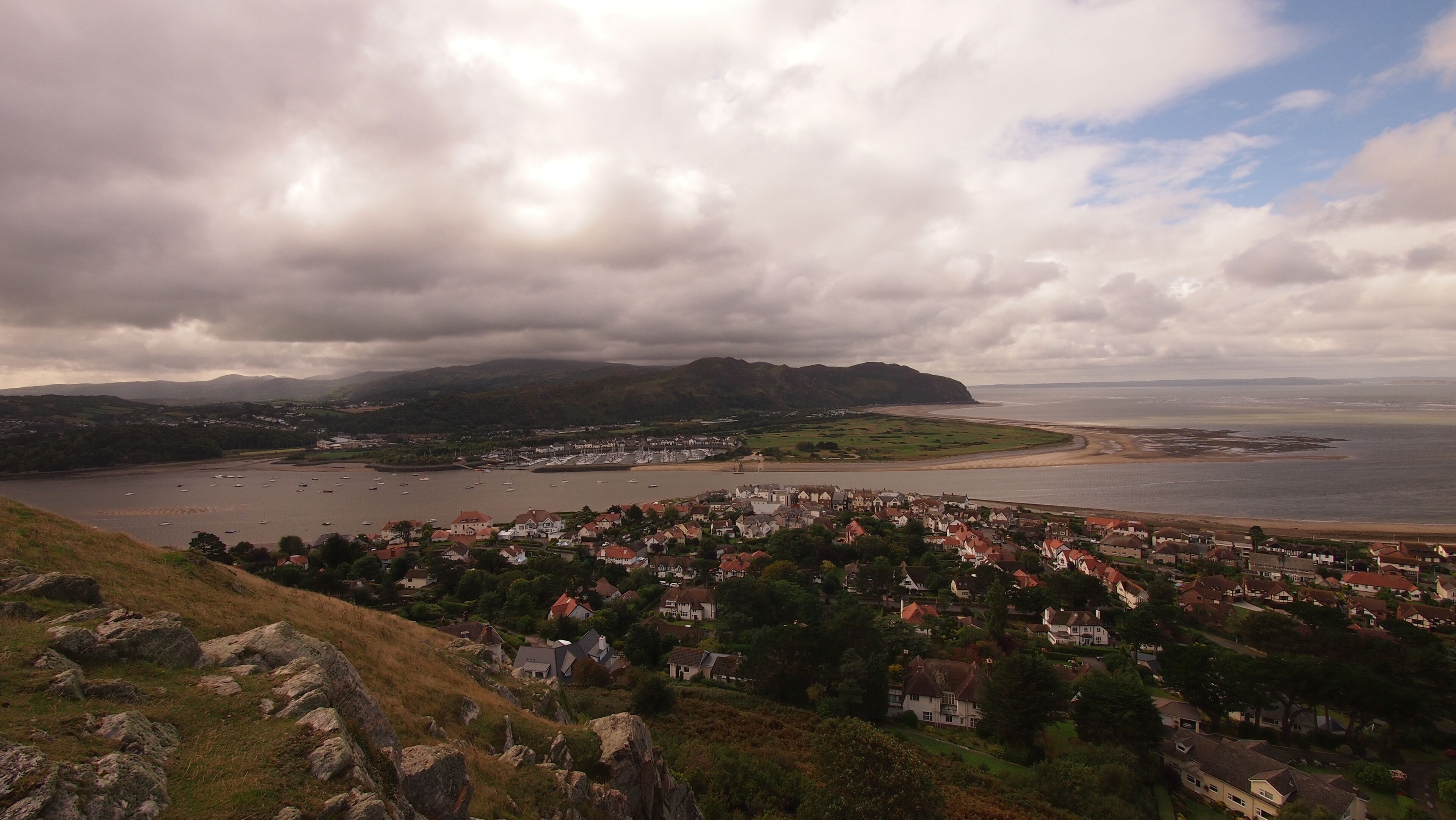 A coastal town with a bay, boats, and a mountainous backdrop.