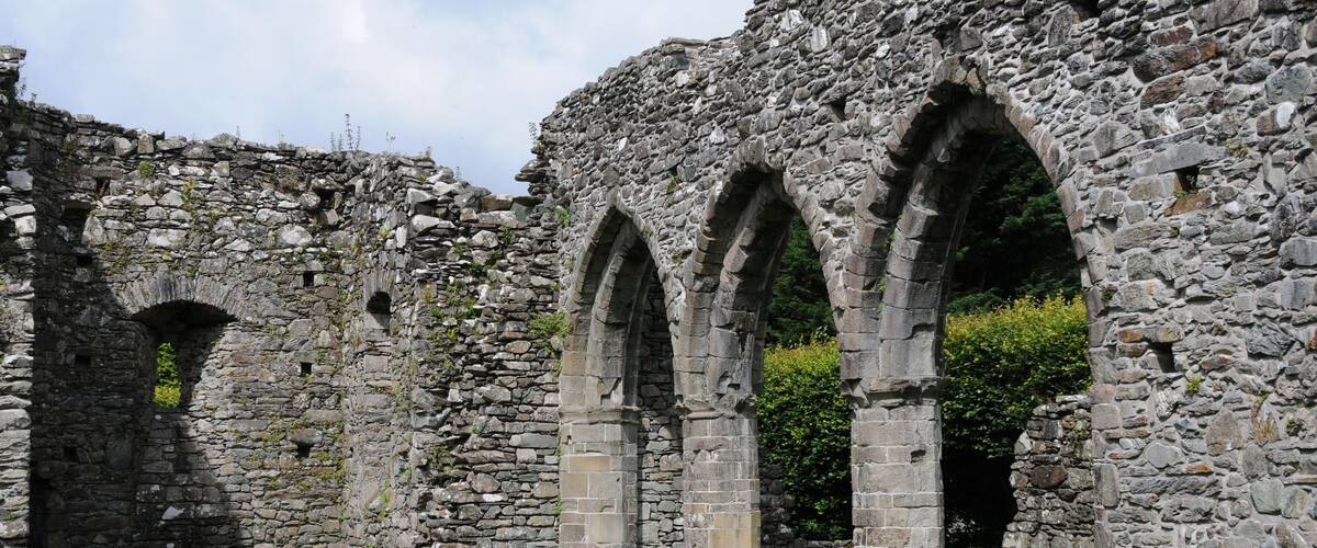 Ancient stone ruins with arches and a grassy area.