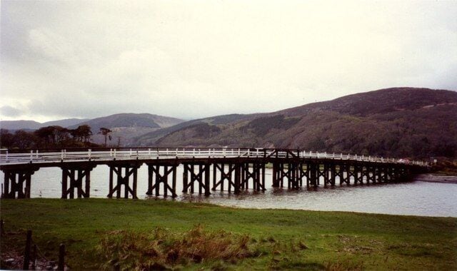 A long bridge over a river with hills in the background.