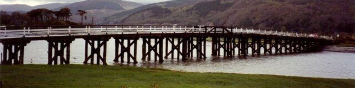 Eine lange Brücke über einem Fluss, mit Hügeln im Hintergrund.