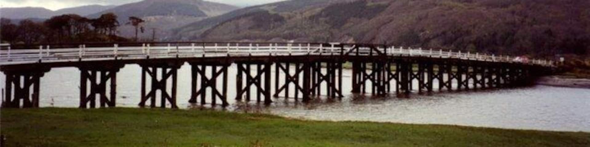 A long bridge over a river with hills in the background.