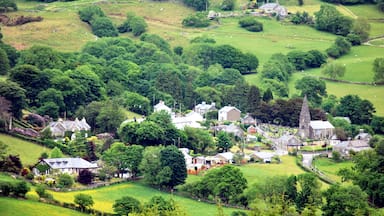 A rural village with houses, a church, and rolling green hills.
