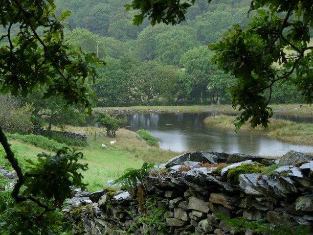 A stone wall, a river, and a forested area with a waterfall.