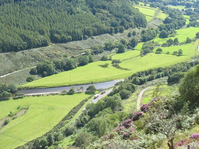 A river winding through green fields, surrounded by forested hills.