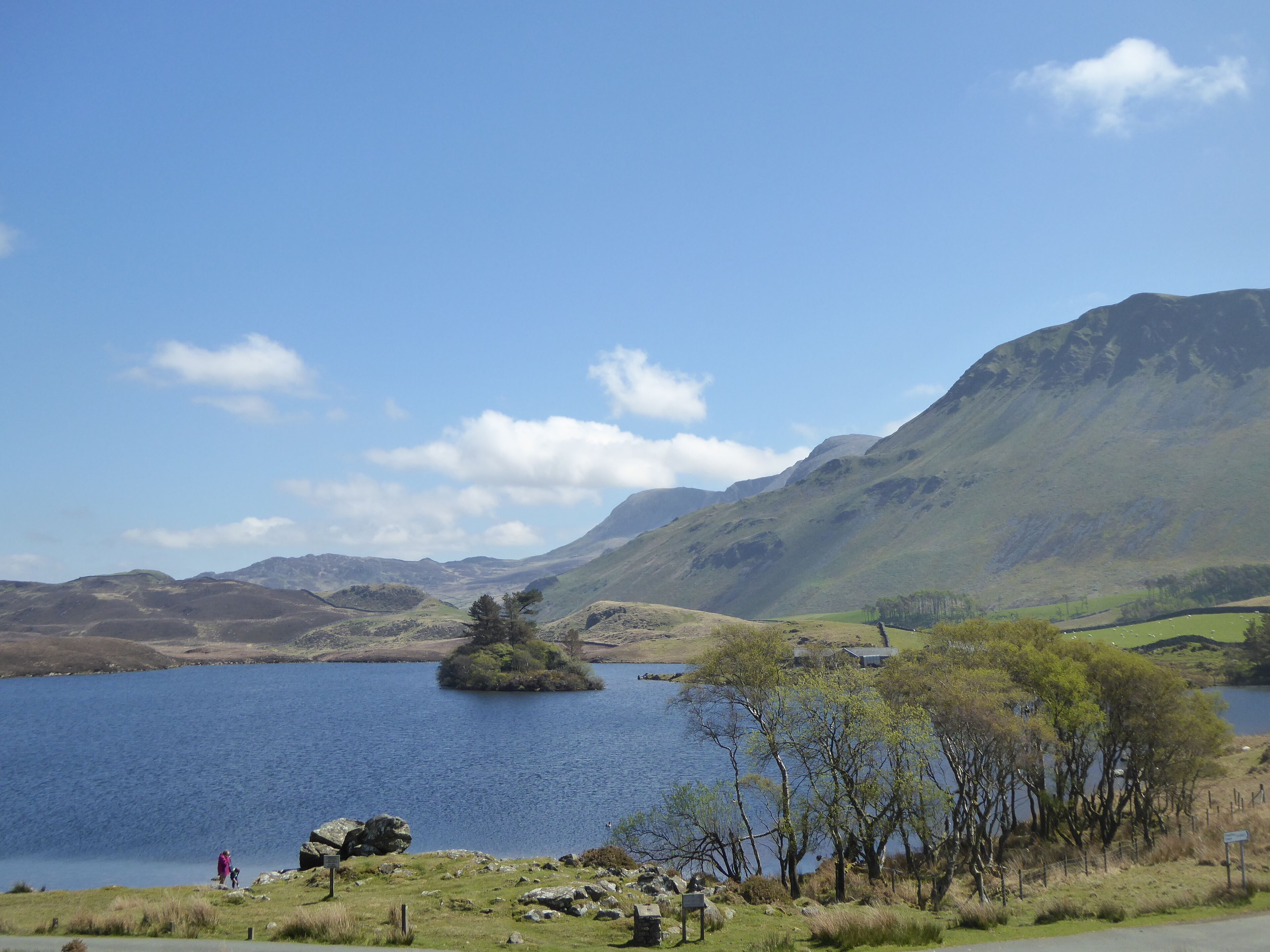 A lake surrounded by mountains and a small island with trees.