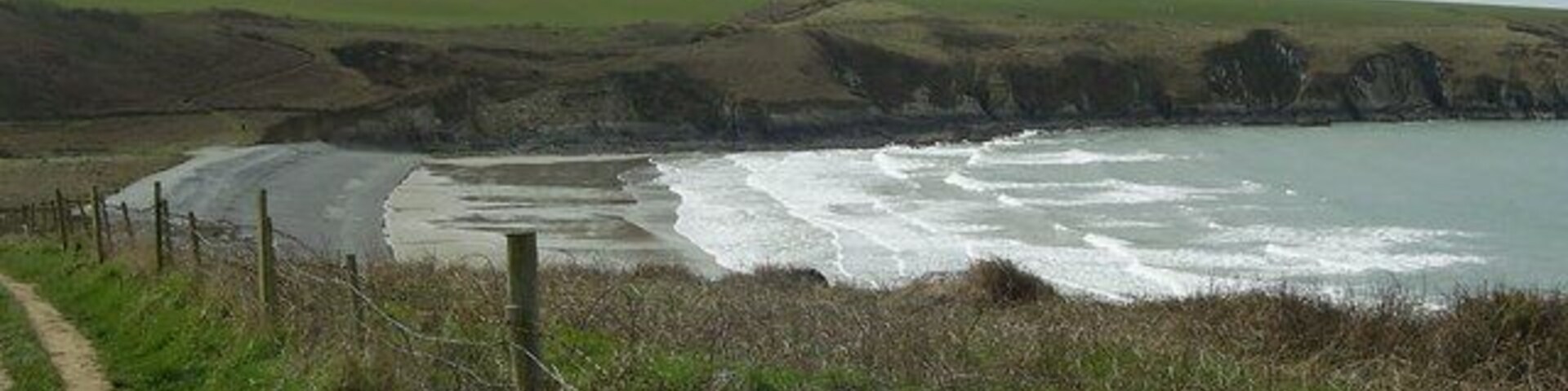 Abermawr beach The pebble bank and exposed sand can be seen at low tide.The Pembrokeshire Coast National Park path continues from the gate by the turning circle.Walkers have to cross the pebble bank that runs across the back of the beach to rejoin the path close to a disused quarry.