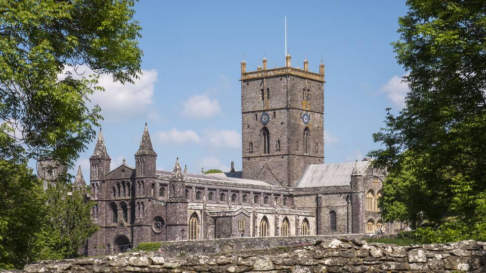 A historic stone church with a tall tower and spires, surrounded by trees.