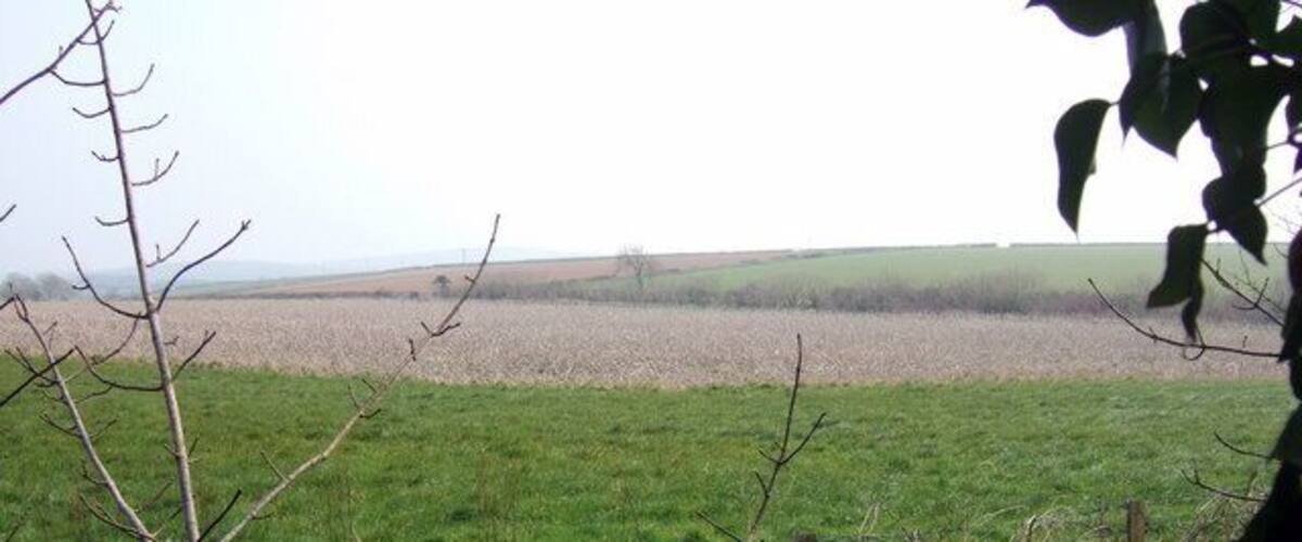 A rural landscape with a field, a fence, and distant hills.