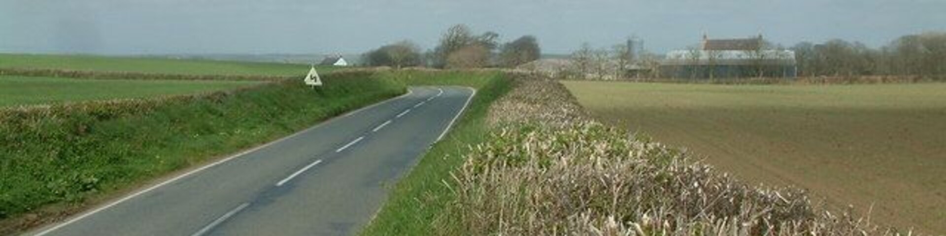 B4327, hedges and fields The B4327 road runs through this square, and is bounded by stone and earth hedges topped with shrubs. Rosepool Farm can be seen in the distance.