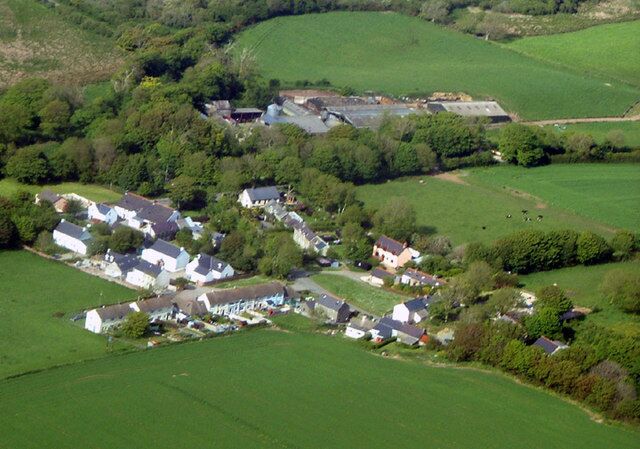 An aerial view of a rural village with houses, fields, and a large building.