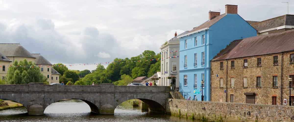 A stone bridge over a river, surrounded by historic buildings, including a blue one with a sign reading "Scott's".