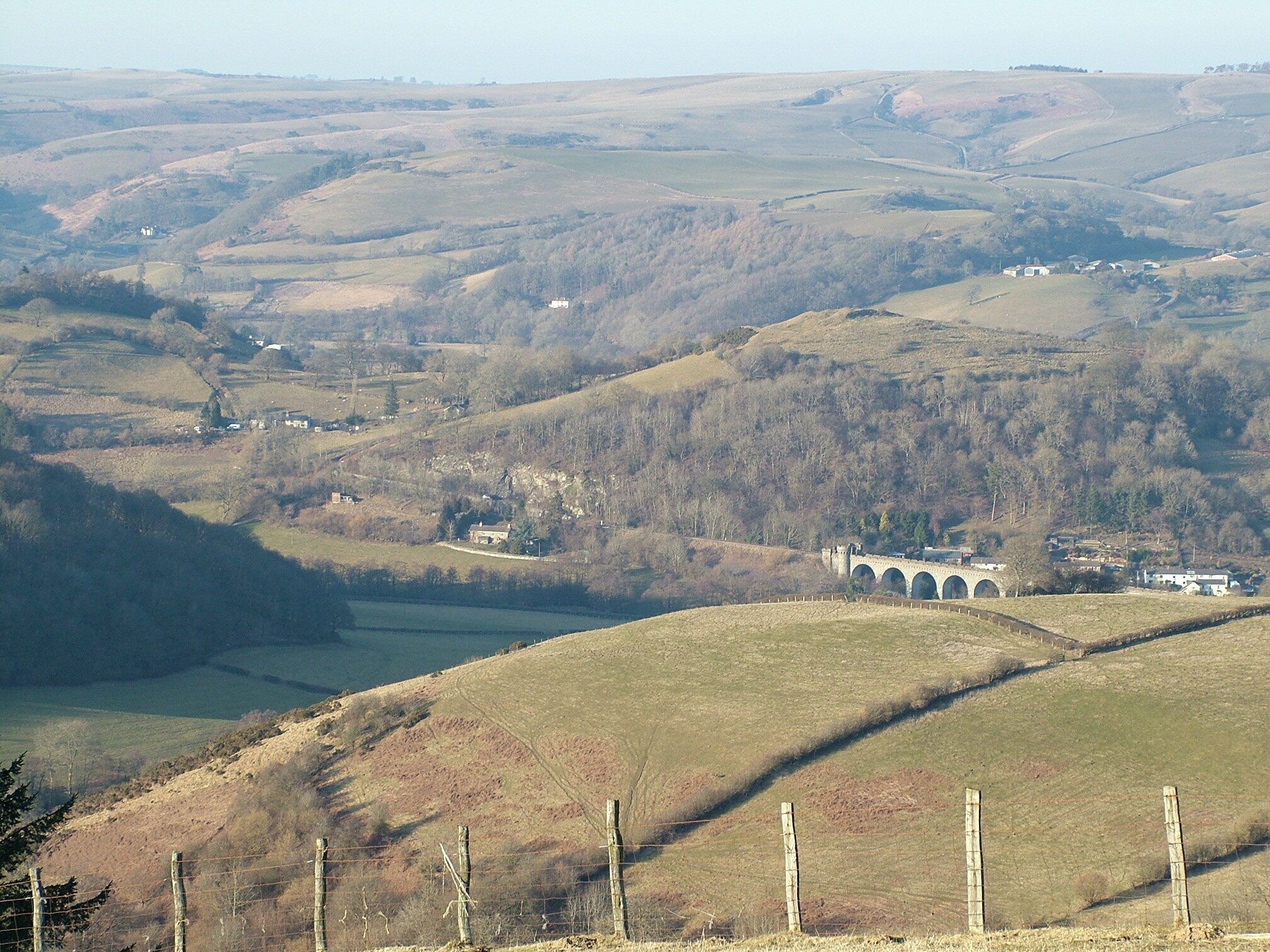 Rolling hills, a stone bridge, and scattered buildings.