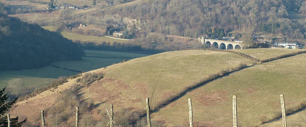 Rolling hills, a stone bridge, and scattered buildings.