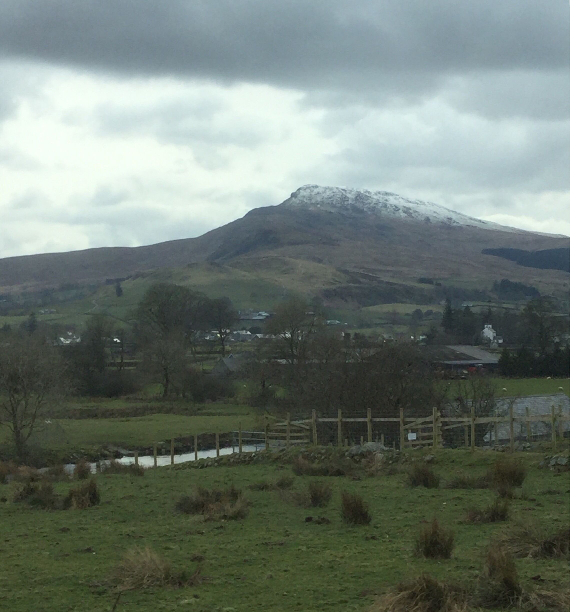 A snow-capped mountain, a river, and a rural landscape with houses.
