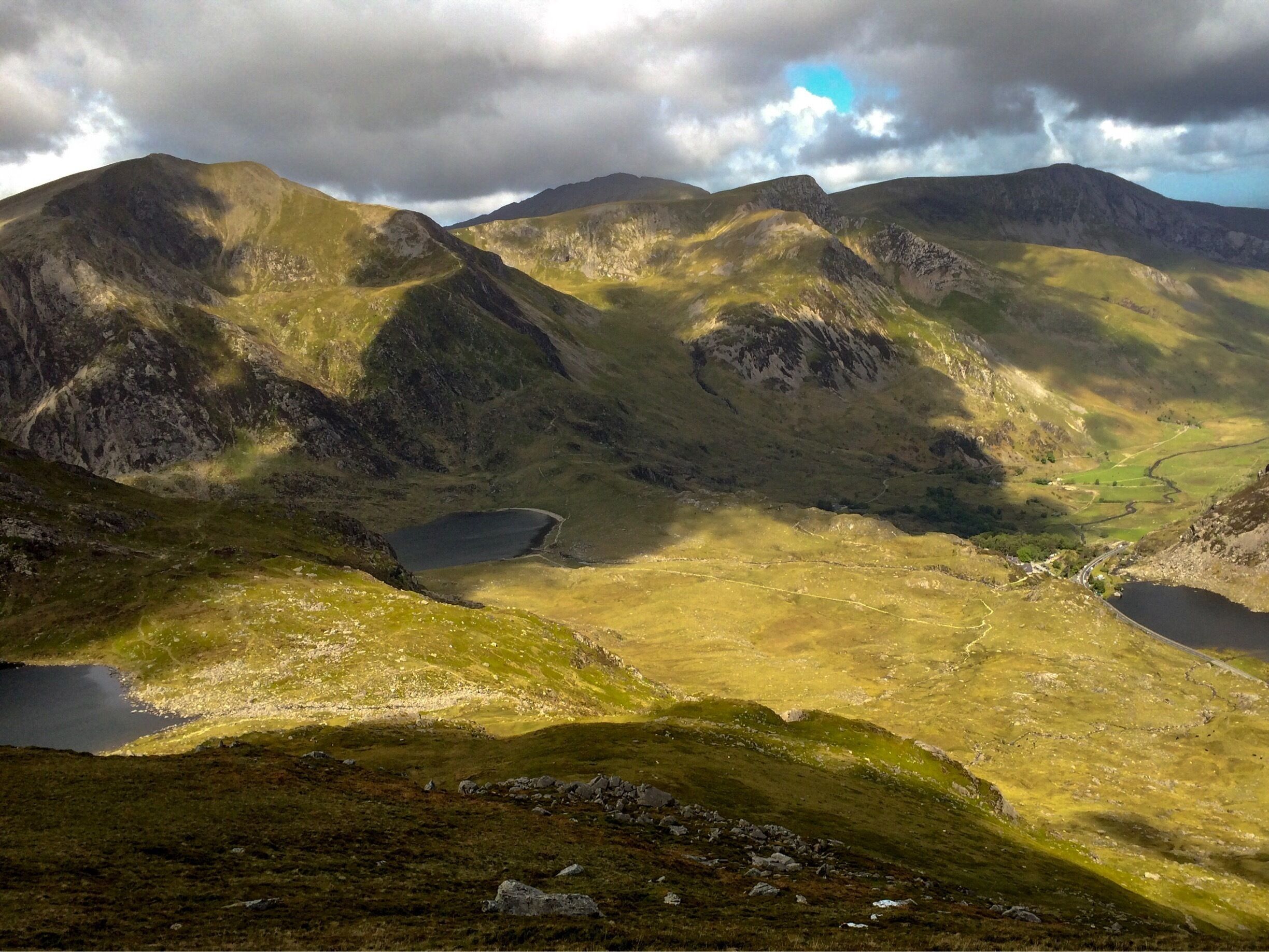 A mountainous landscape with a valley, lakes, and a winding road.