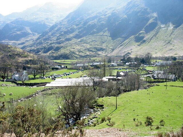 Un paisaje rural con colinas ondulantes, casas dispersas y un pequeño arroyo.