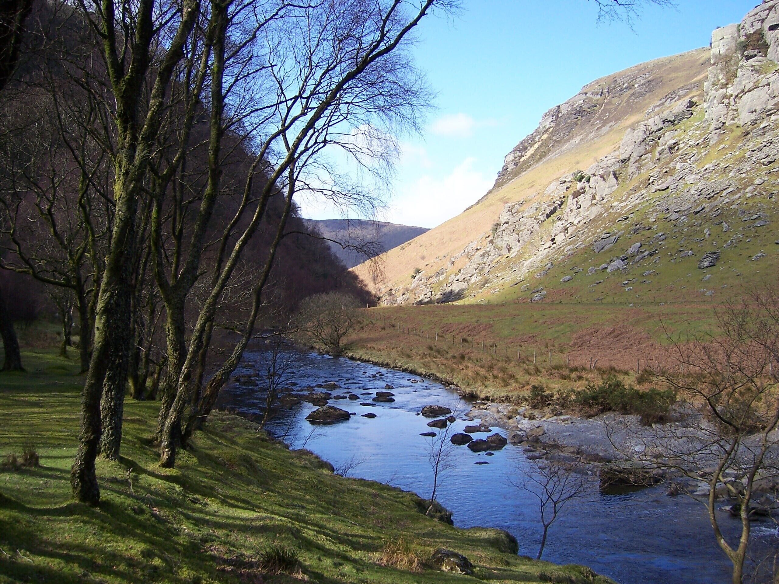 A river flowing through a valley with rocky hills and trees.