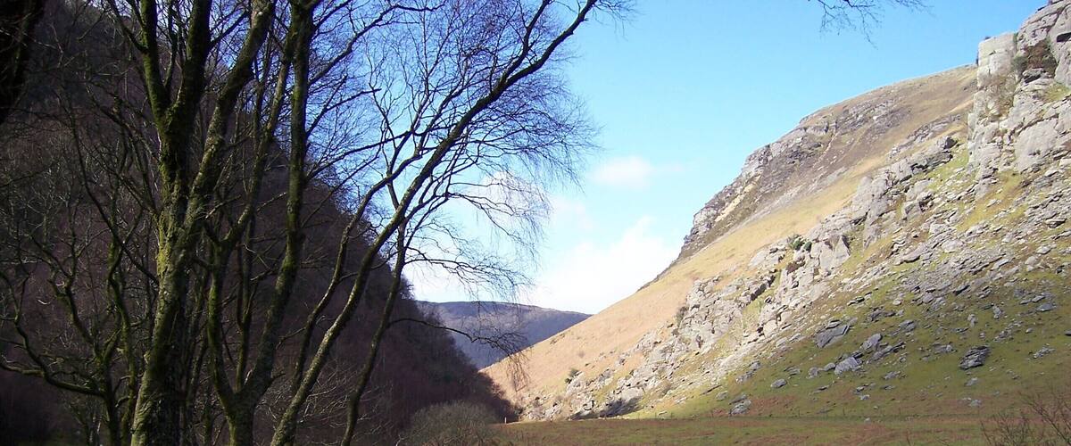 A river flowing through a valley with rocky hills and trees.