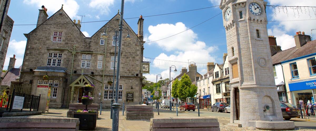 A historic stone building with a clock tower, a bench with flowers, and a sign for the Convent Hotel.