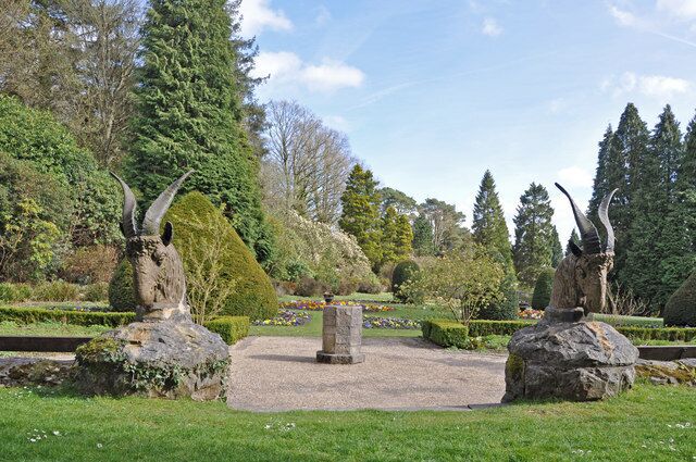 A park with sculptures, a stone monument, and well-maintained lawns.