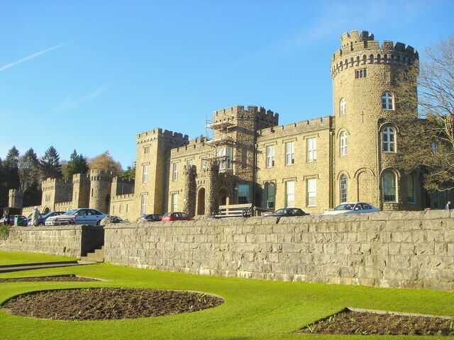 A large castle with multiple towers and a stone wall in front.