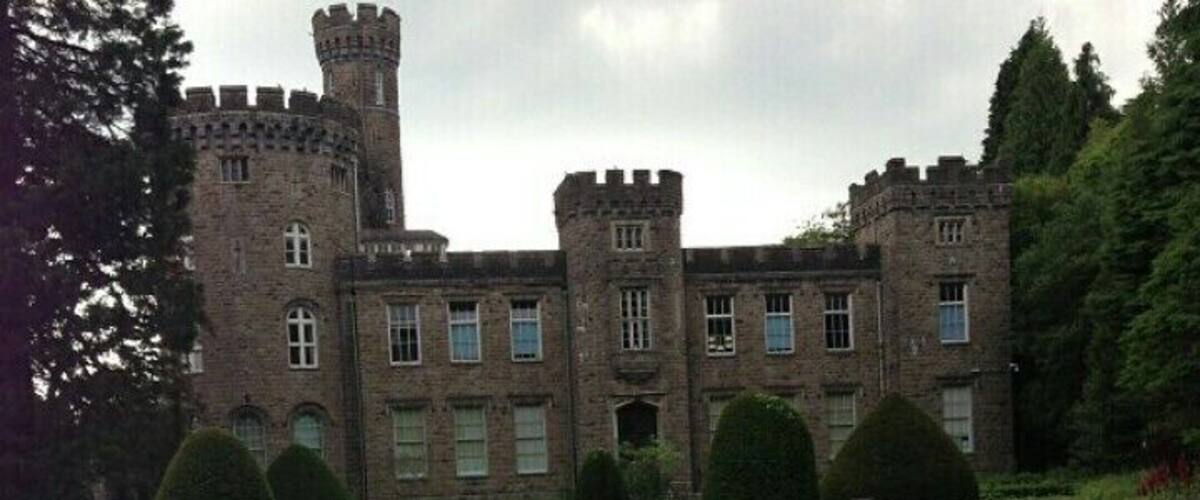 A castle with a tower, surrounded by manicured gardens and hedges.