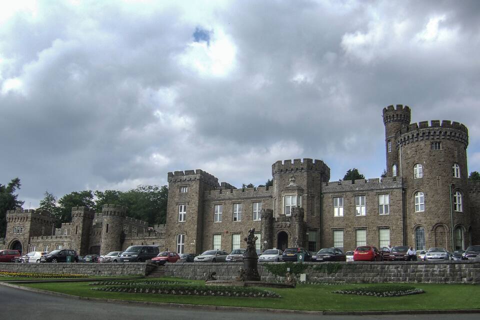 A historic castle with multiple towers and a well-maintained garden.