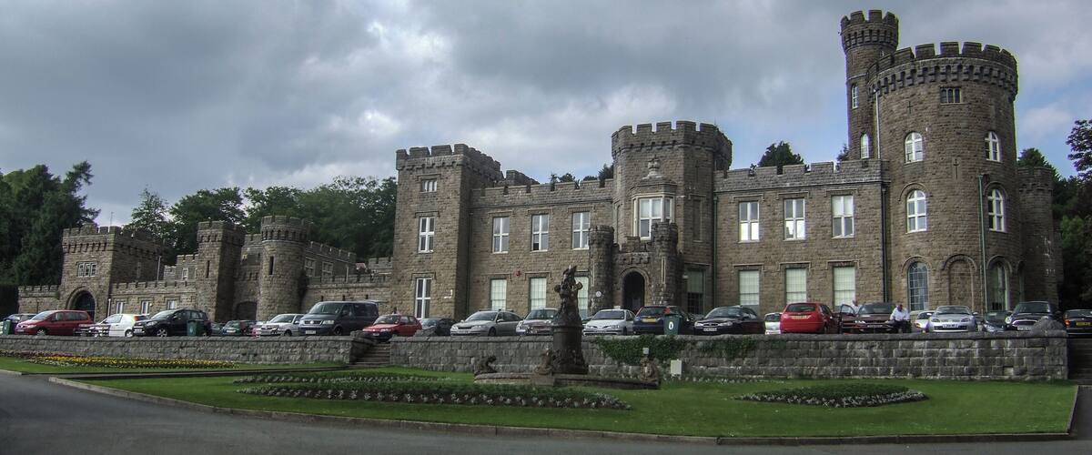 A historic castle with multiple towers and a well-maintained garden.