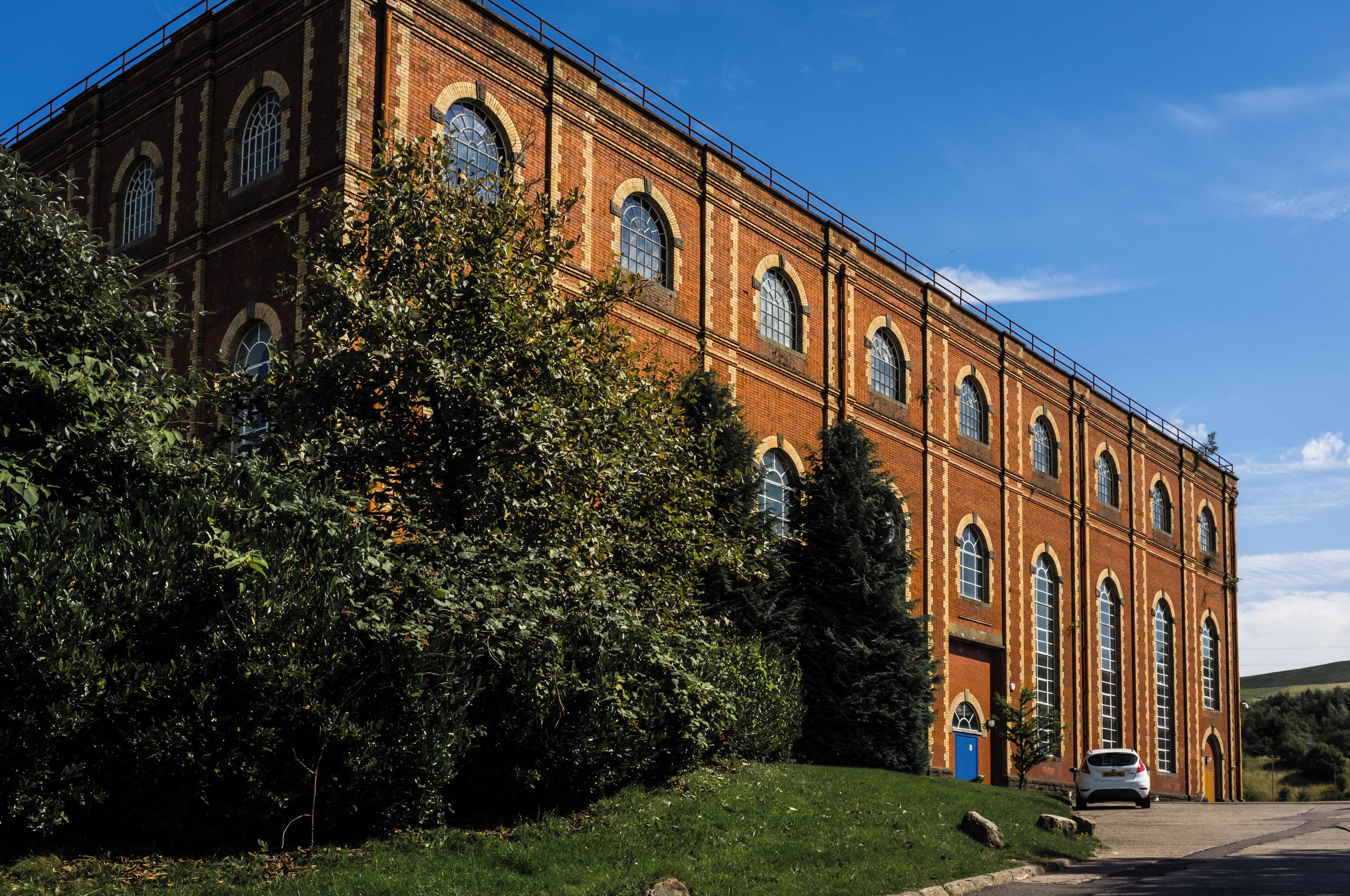 A large brick building with arched windows and a car parked in front.