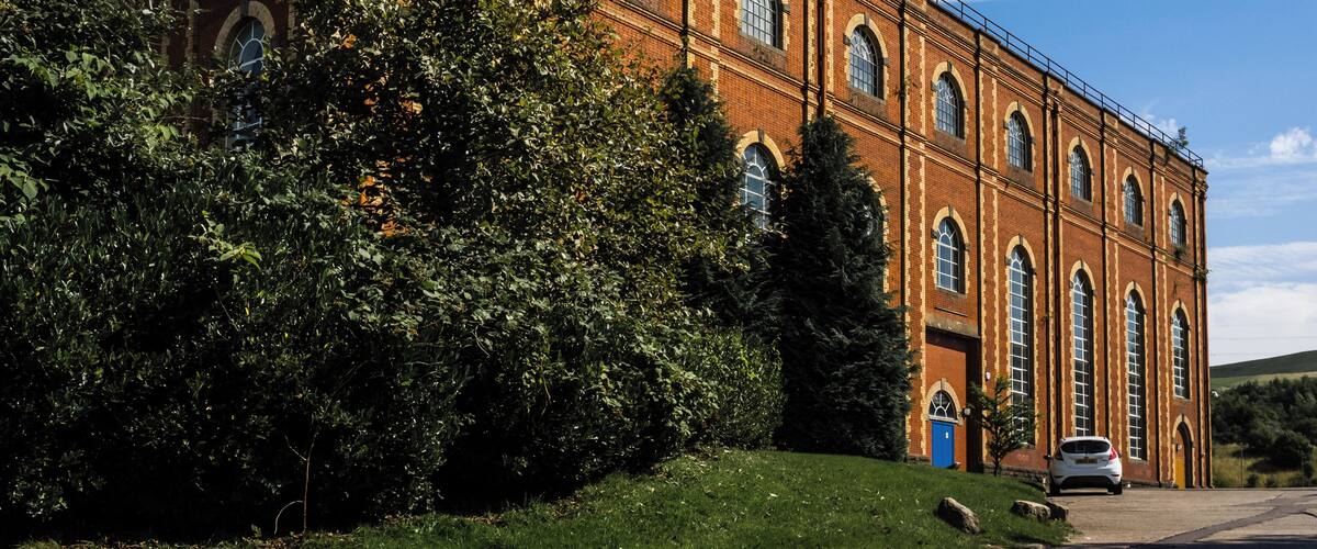 A large brick building with arched windows and a car parked in front.