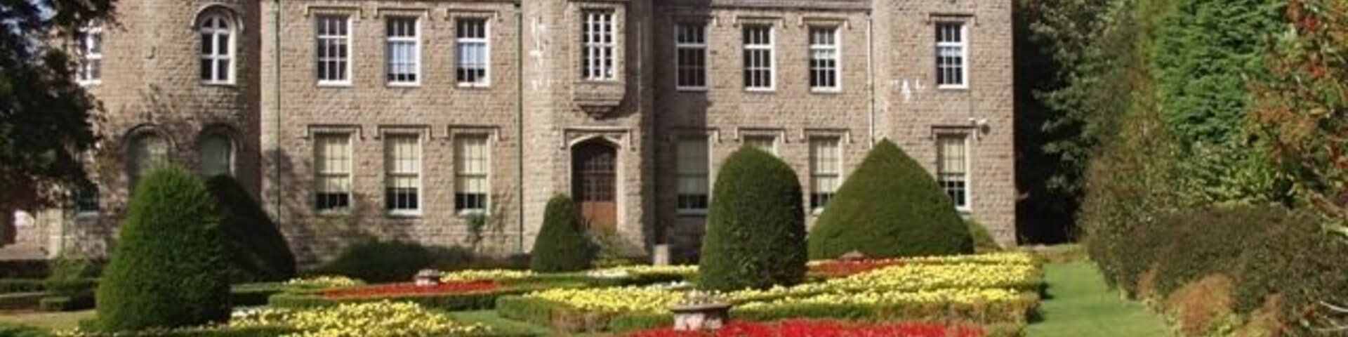 A castle with a tower, surrounded by manicured gardens and hedges.