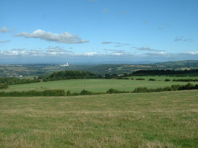 A grassy field with a distant view of a tower and rolling hills.