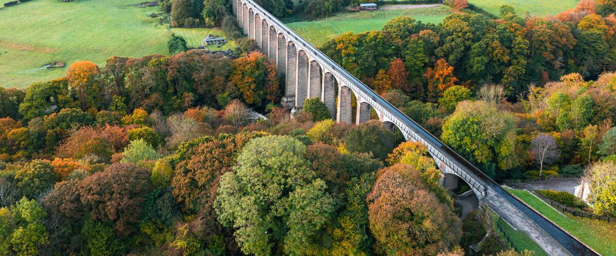 A viaduct over a river, surrounded by autumn foliage and rural landscapes.