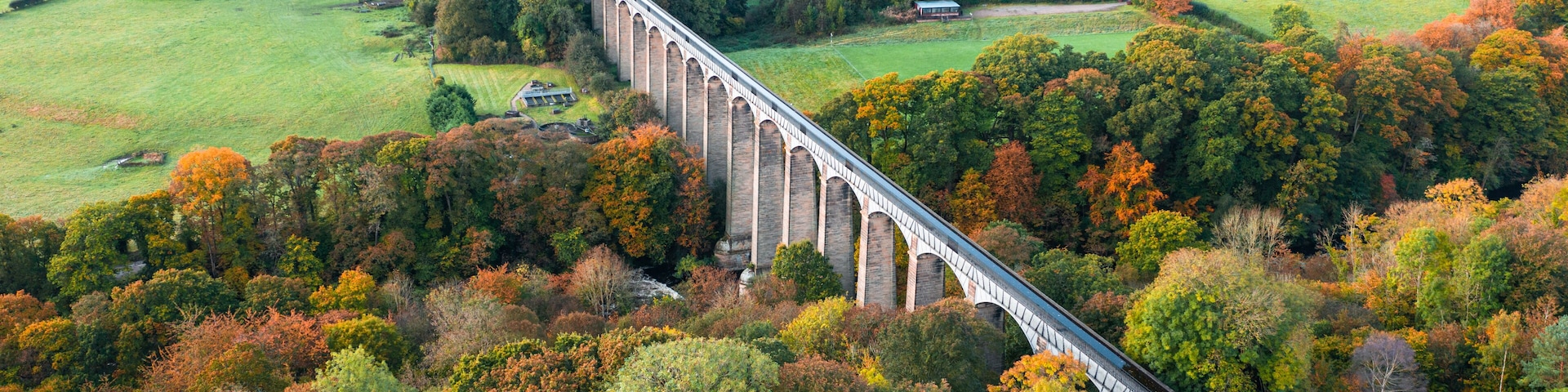 A viaduct over a river, surrounded by autumn foliage and rural landscapes.