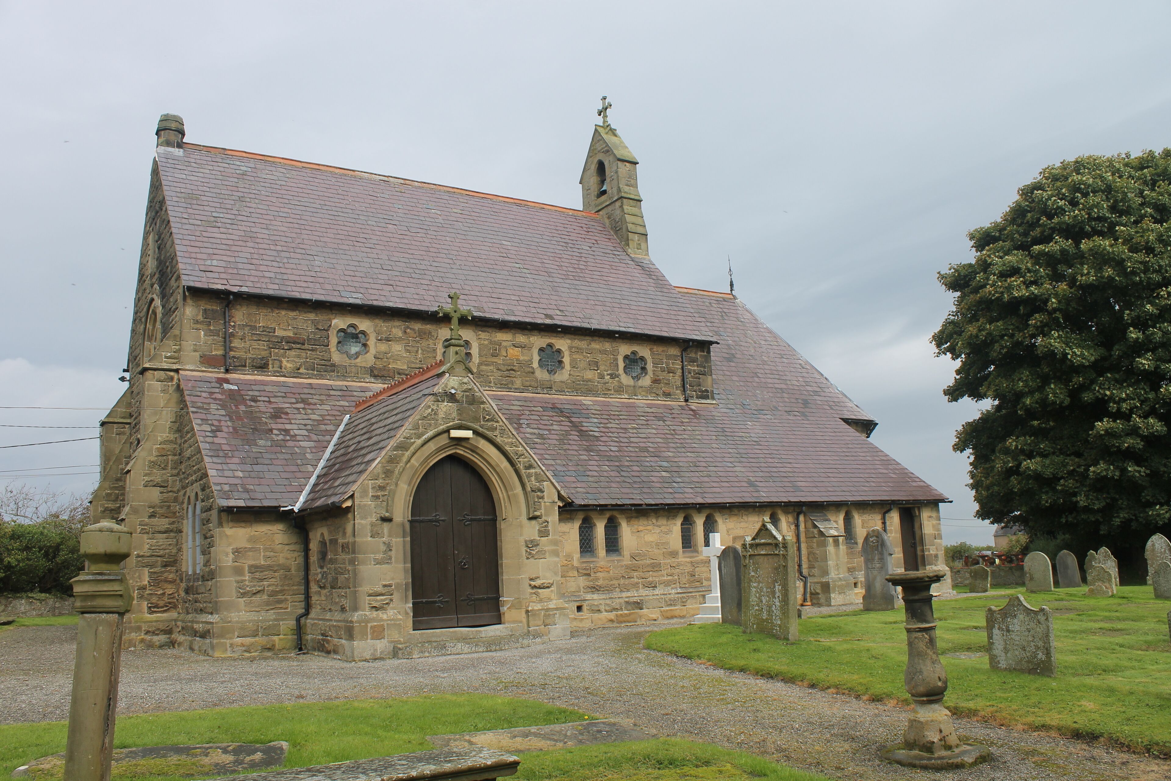 A stone church with a steep roof and a large arched entrance.