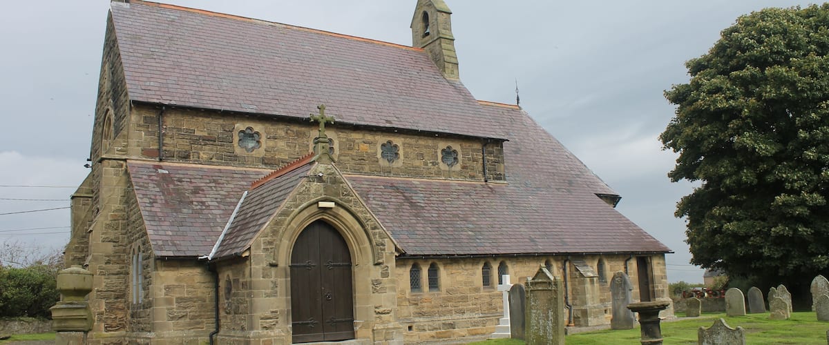 A stone church with a steep roof and a large arched entrance.