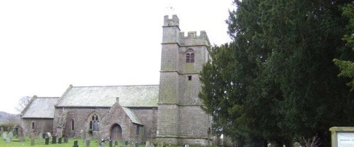 A church with a tall tower and a graveyard in front.