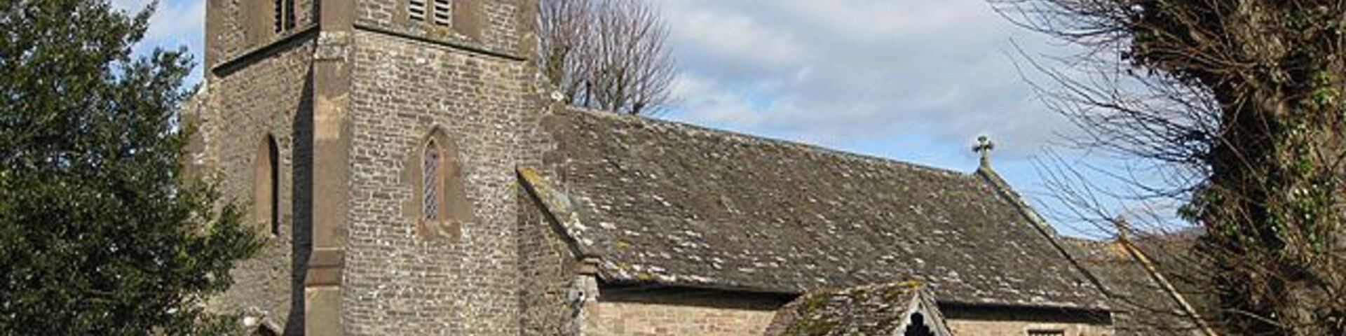 View to the Northeast of St. Dingat's Church The church is in the Early English and Perpendicular styles, consisting of chancel, nave, north transept, south porch and an embattled western tower with pinnacles containing 6 bells: the church was thoroughly restored, reseated and was re-roofed in 1887-8. Dedicated to St. Dingat (Welsh Dingad).