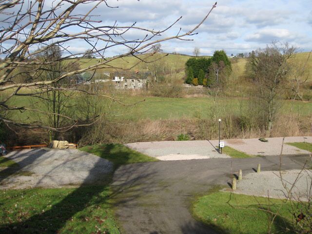 View from the churchyard across the River Trothy The areas of hardstanding are the riverside caravan pitches. This view will probably be obscured in the holiday season.