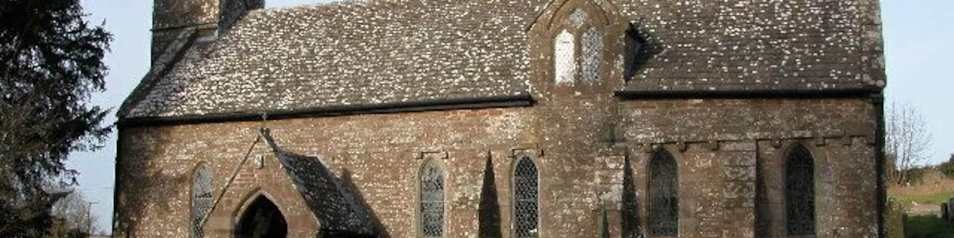 Welsh Newton church. Welsh Newton church is dedicated to St Mary the Virgin and is one of a few English churches with a saint buried in its graveyard, St. John Kemble. The village is on the England/Wales border, lying just in England.