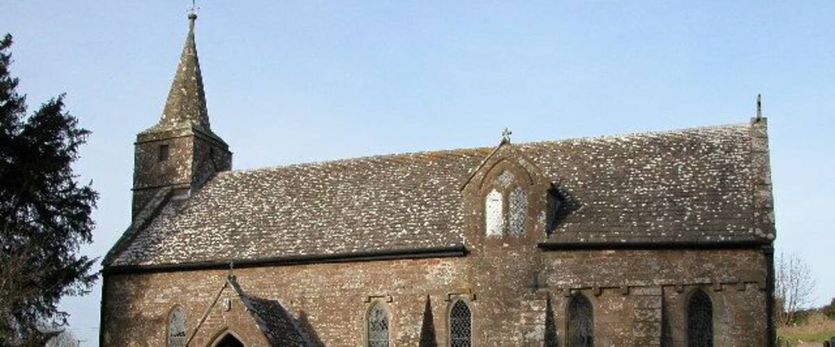 A historic church with a tall steeple, arched windows, and a graveyard in front.