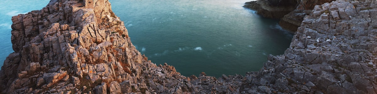 Eine zerklüftete Küstenlinie mit Felsen und ruhigem Meer.