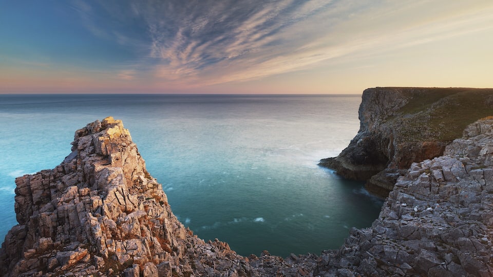 A rugged coastline with rocky cliffs and a calm sea.