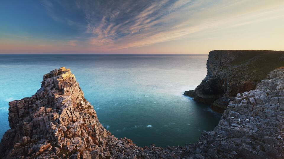 A rugged coastline with rocky cliffs and calm sea.